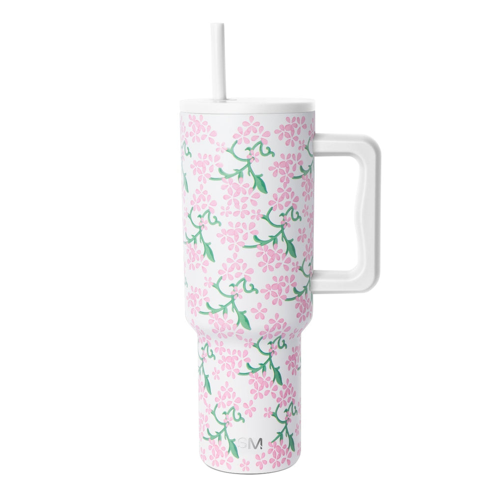 White insulated tumbler with handle and lid featuring pink flowers and green foliage pattern, Simple Modern logo, against white background.